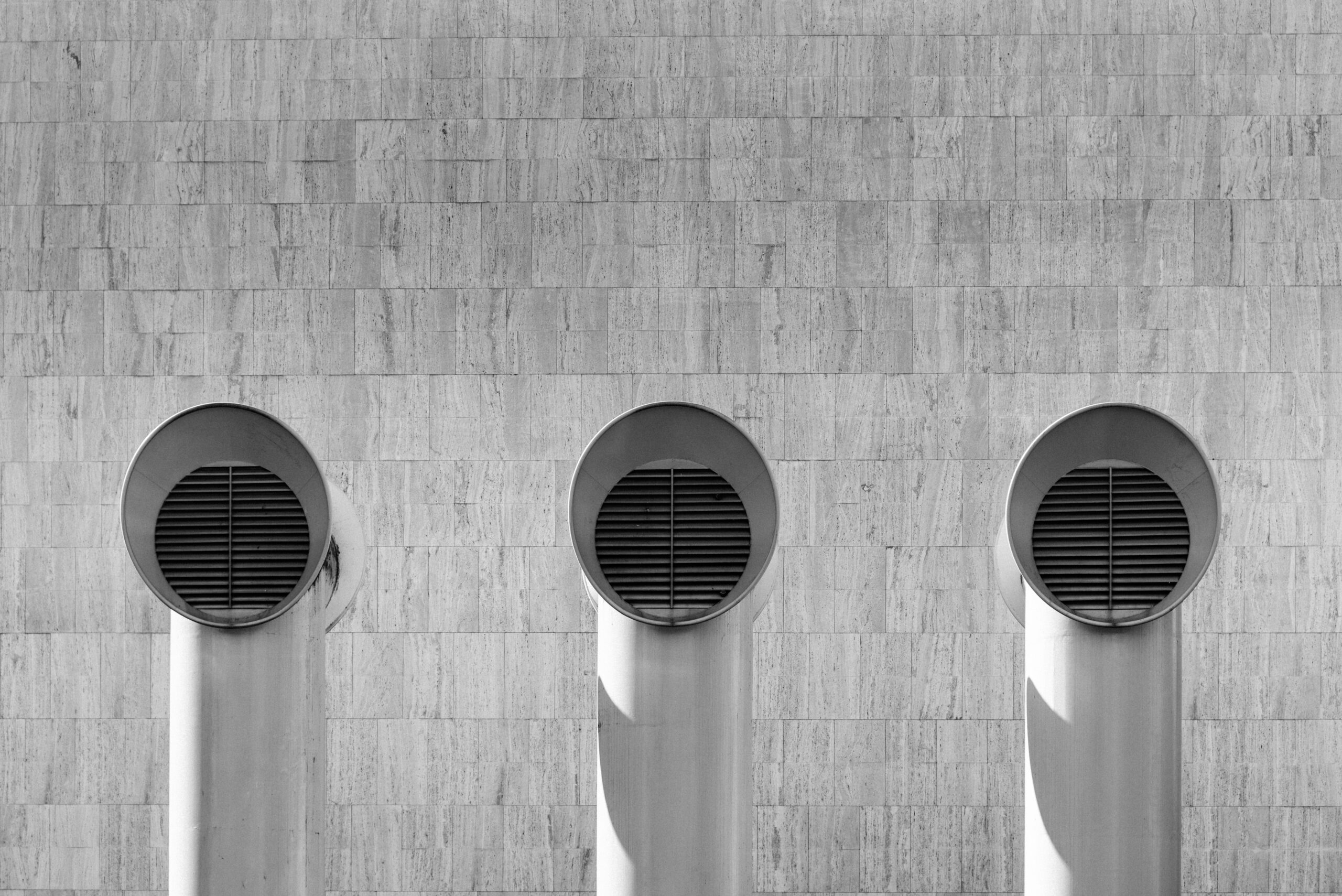 Three round windows on a wall with shadows.