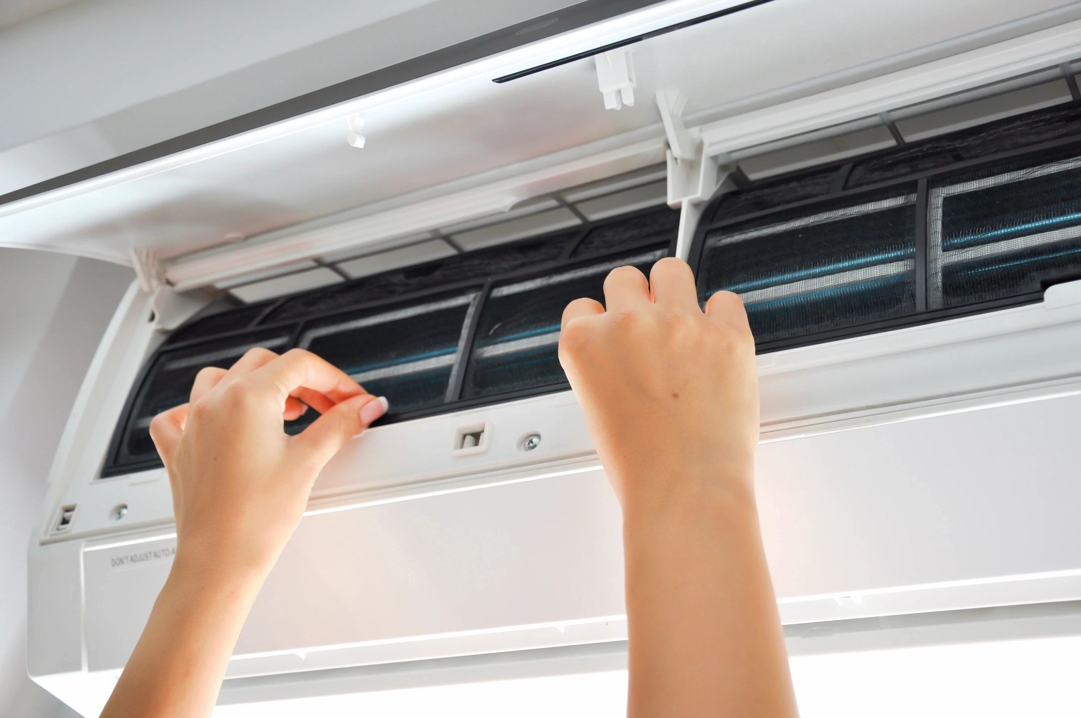 A person is cleaning the air conditioner with a brush.