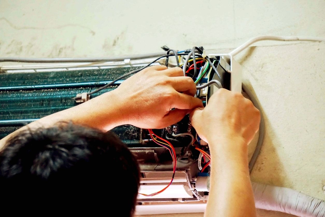 A person working on wires in front of an electrical box.